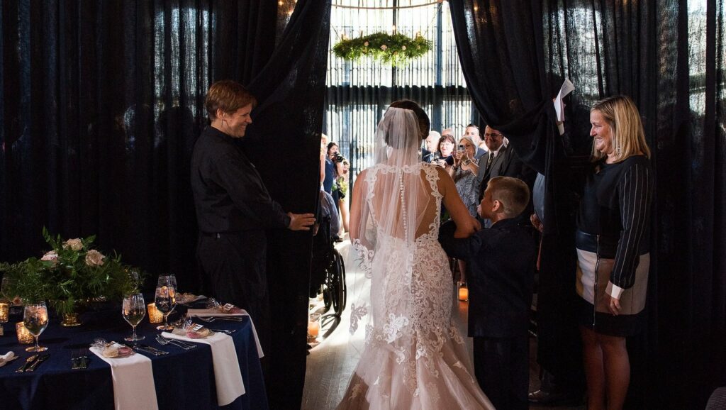 Together & Company employees hold open the curtains for a bride to walk down the aisle at her High Line Car House wedding ceremony
