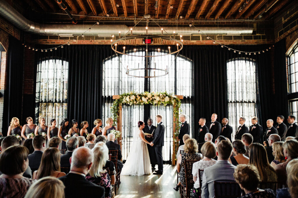 High Line Car House industrial wedding ceremony in front of floor to ceiling windows. 