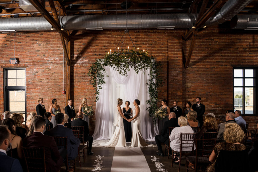 LGBTQ wedding ceremony at High Line Car House, with exposed brick, industrial beams, and historic industrial charm