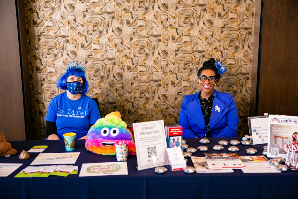 Two people sit at a booth set up at a nonprofit event at The Fives